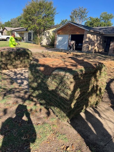 Pallets of fresh sod delivered to a prepared front yard with crew at work