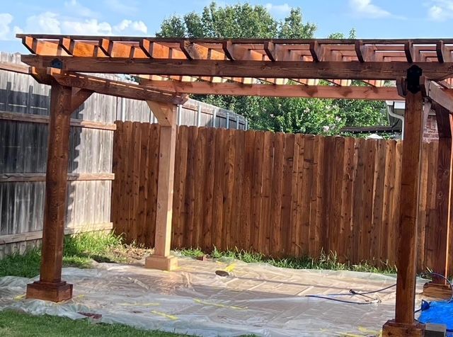 Freshly stained cedar pergola over a covered slab with a matching stained fence
