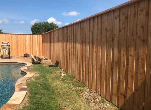 New tall cedar privacy fence surrounding a backyard pool and lawn