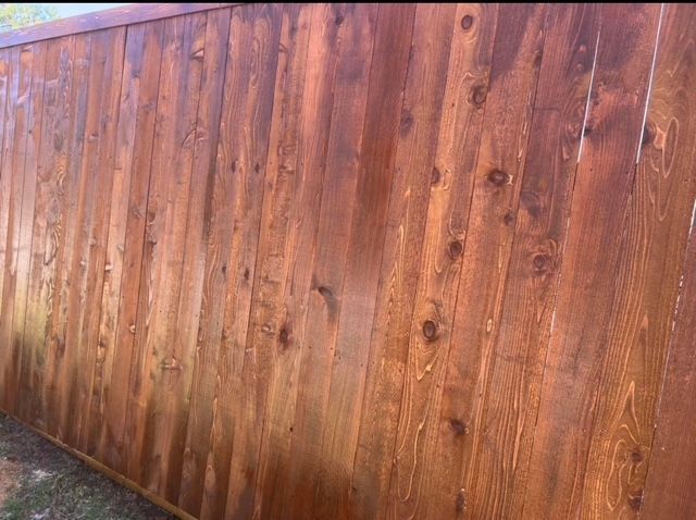 Close view of a freshly stained cedar picket fence showing rich wood grain