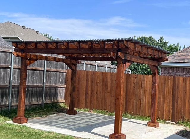 Finished stained cedar pergola with metal roof panels over a concrete patio