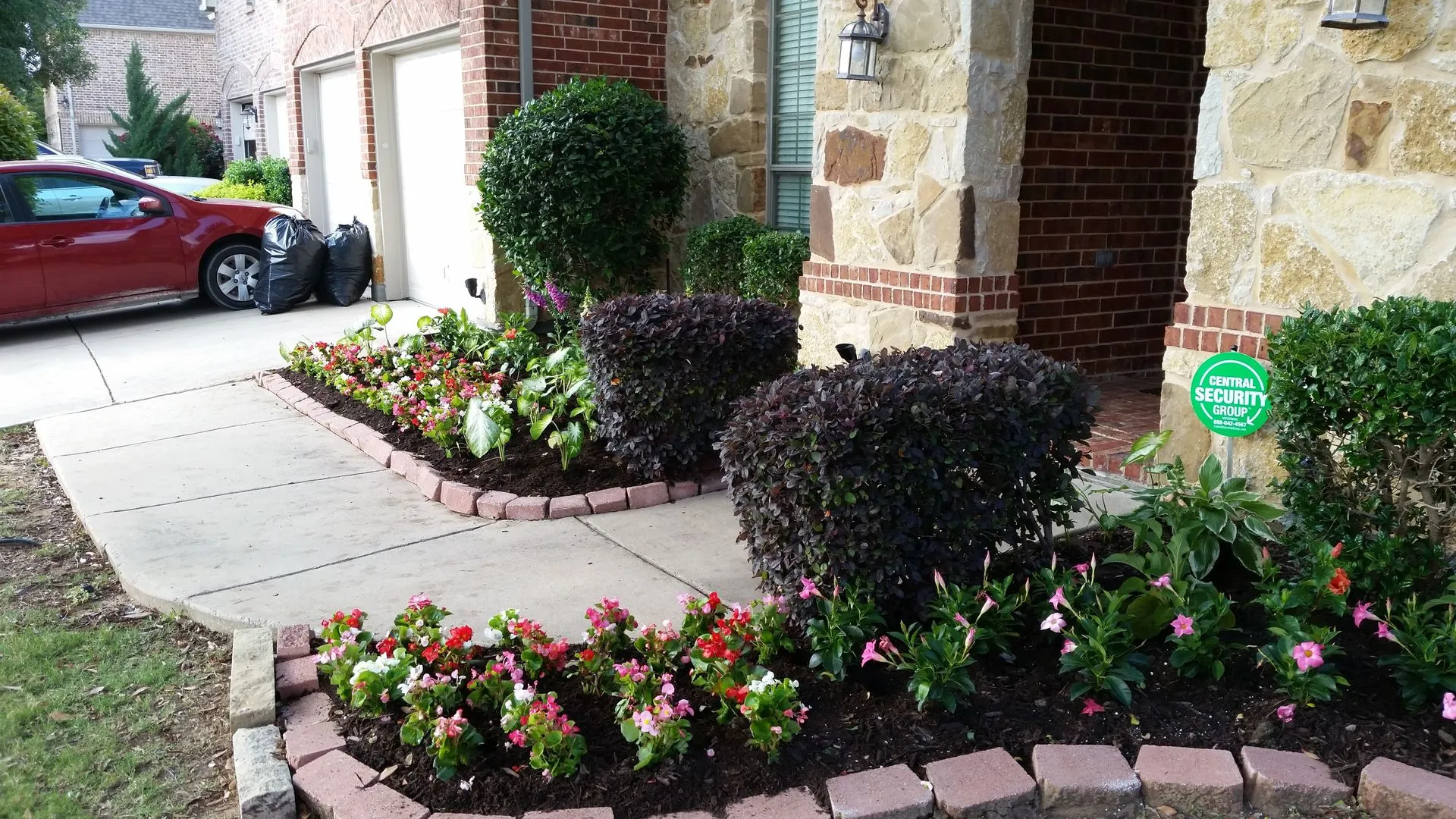Entry flower beds bordered with stone pavers beside a stone home