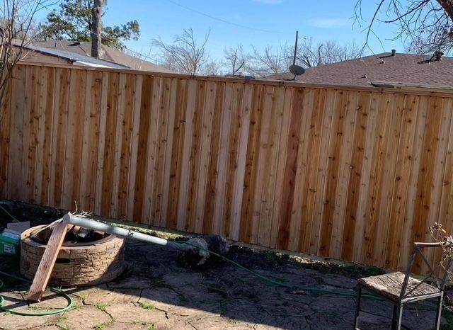 New cedar privacy fence behind a flagstone patio and stone fire pit