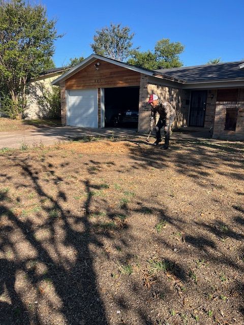 Crew member clearing and leveling a bare front yard before sod installation
