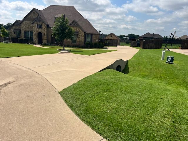 Neatly edged green slopes along a long curved driveway