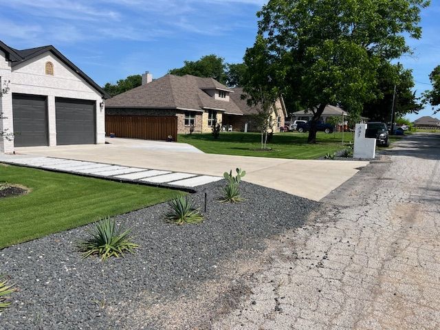 Black gravel bed with yuccas and agave along a new driveway and sod lawn